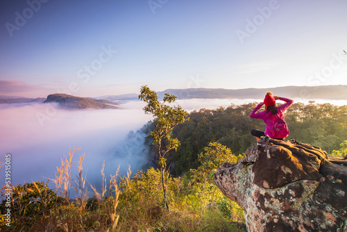 Fototapeta Naklejka Na Ścianę i Meble -  Young woman in red jacket hiking on Pha Muak mountain, border of Thailand and Laos, Loei province, Thailand.