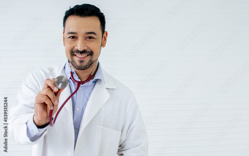 Portrait Asian handsome male doctor with beard wearing white ground uniform, holding stethoscope, smiling with kindness, happiness, posing with copy space. Health and Medical Concept. Portrait Asian handsome male doctor with beard wearing white ground uniform, holding stethoscope, smiling with kindness, happiness, posing with copy space. Health and Medical Concept.