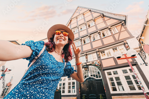 Happy girl traveller taking selfie photos against traditional half-timbered architecture in old European town photo