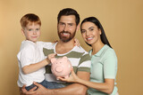 Happy family with ceramic piggy bank on beige background
