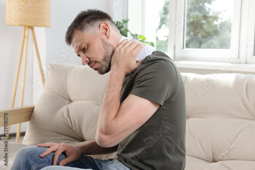 фотографія Man using heating pad on sofa at home