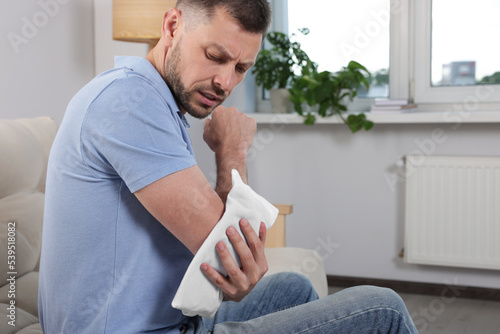 Man using heating pad at home, space for text