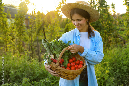 Woman with basket of different fresh ripe vegetables on farm