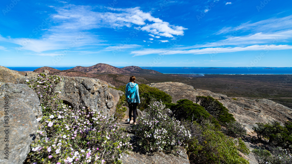 brave backpacker girl celebrates summiting frenchman peak in cape le grand national park in western australia, hiking and climbing the mountain with her backpack