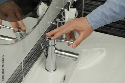 Man using water tap in bathroom  closeup