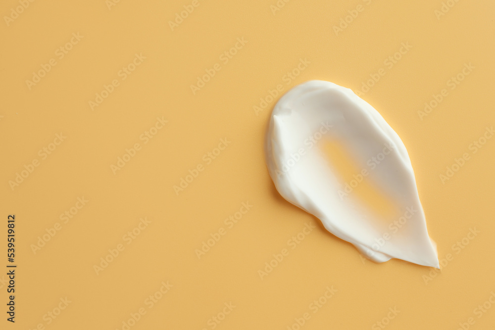 Naklejka premium Sample of face cream on yellow background, top view. Space for text