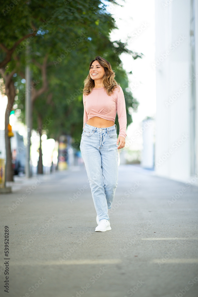 Full length happy young woman walking on street