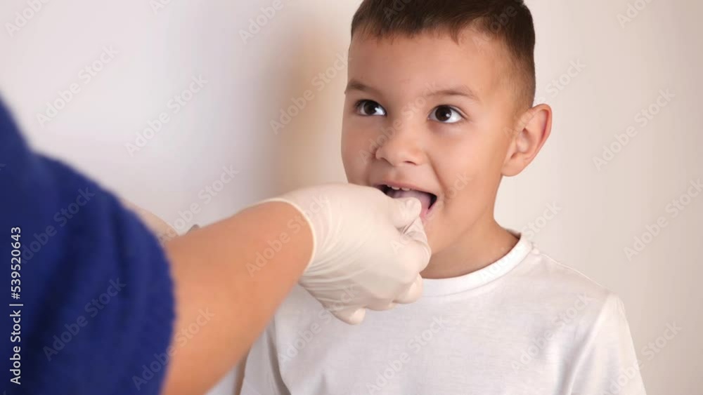 A little boy is given a throat lozenge. A little boy is given a throat lozenge.