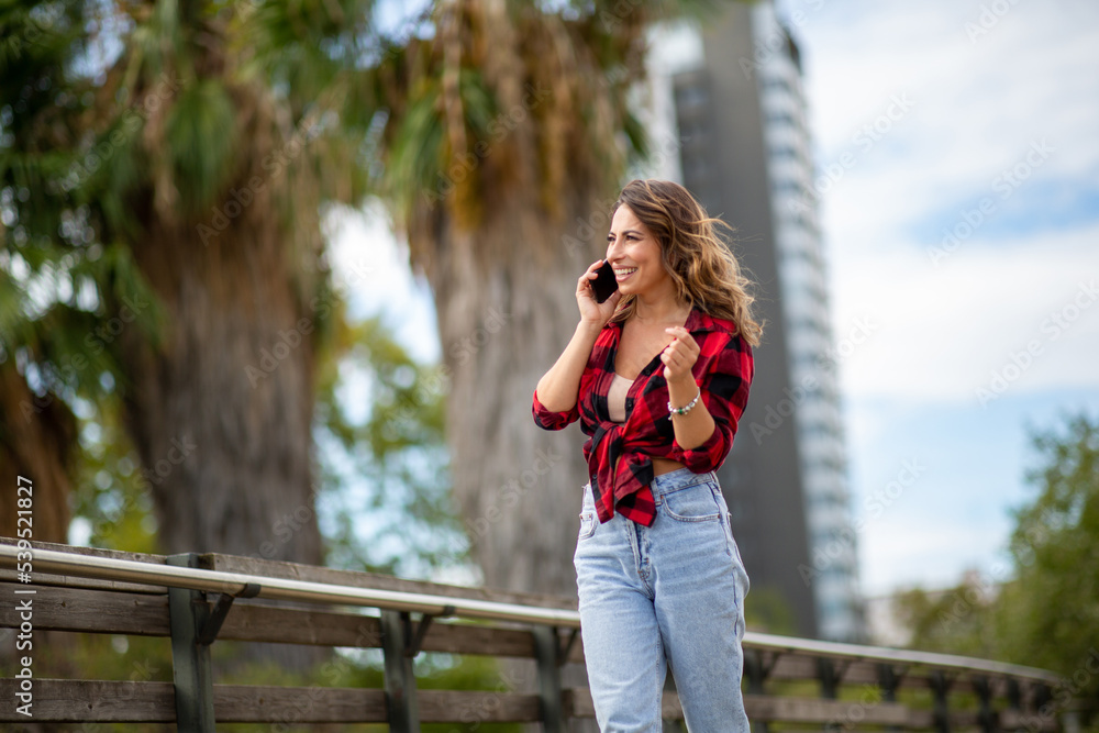 happy woman walking and talking with cellphone outdoors