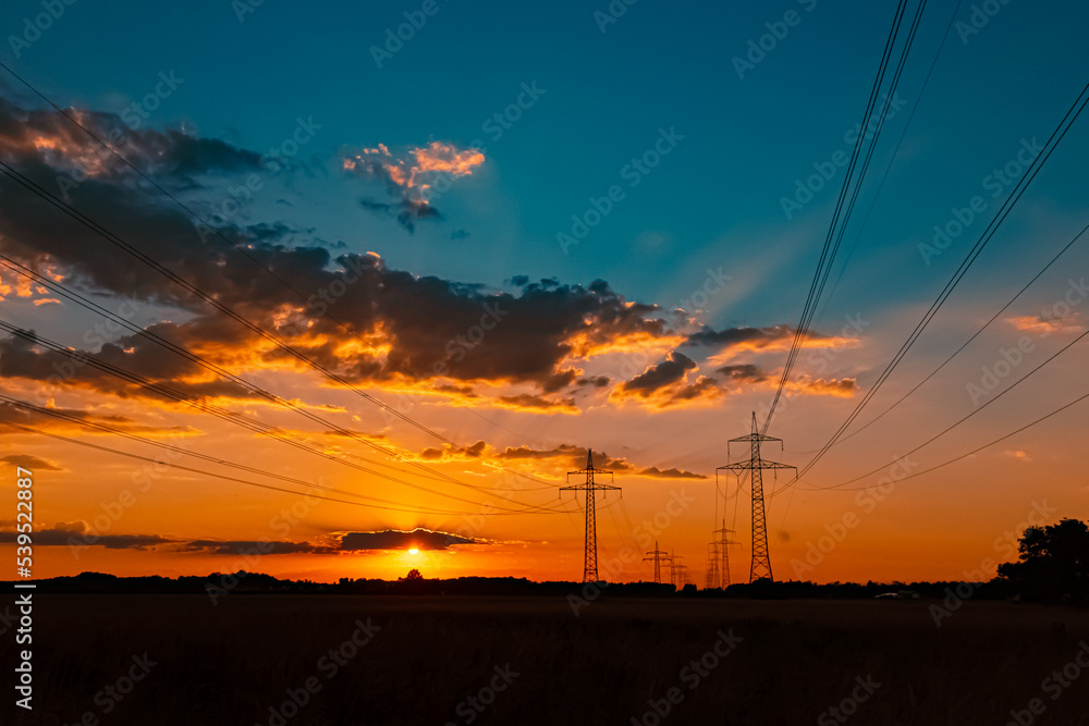 Naklejka premium Beautiful sunset with a dramatic sky and overland high voltage lines near Tabertshausen, Bavaria, Germany