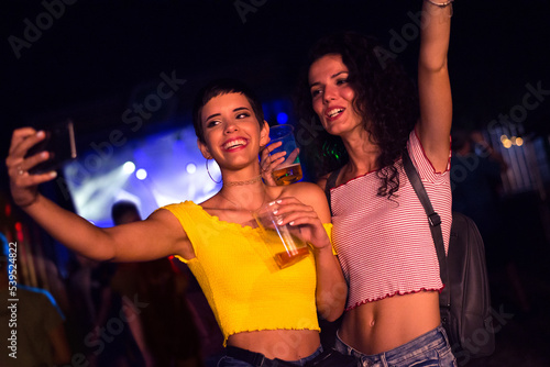 Photography Two happy young girls dancing and drinking beer on the party concert in the nigh