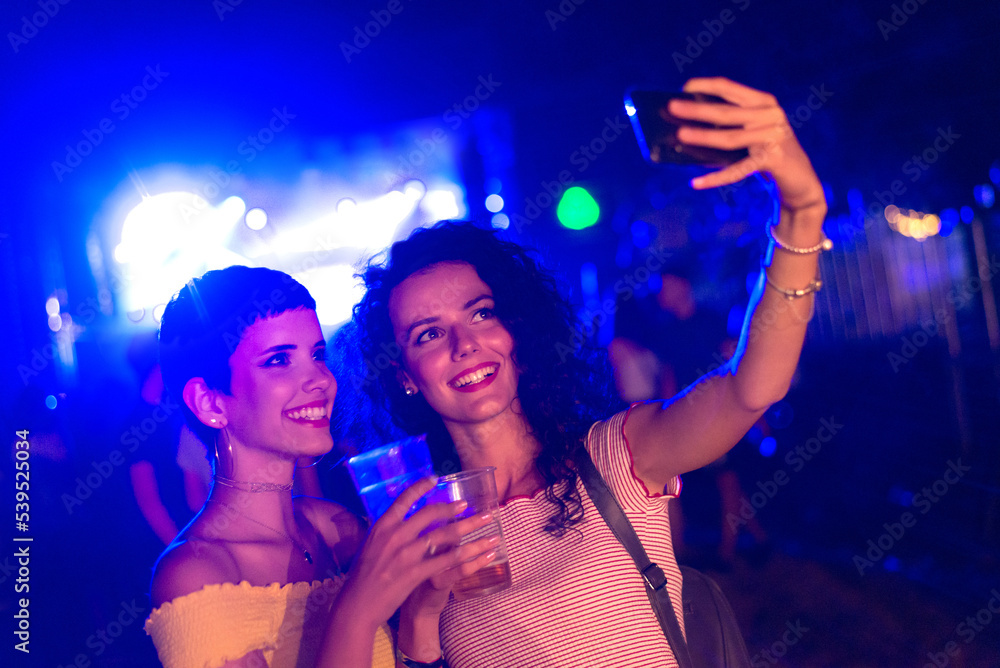 Two happy young girls dancing and drinking beer on the party concert in the night club	