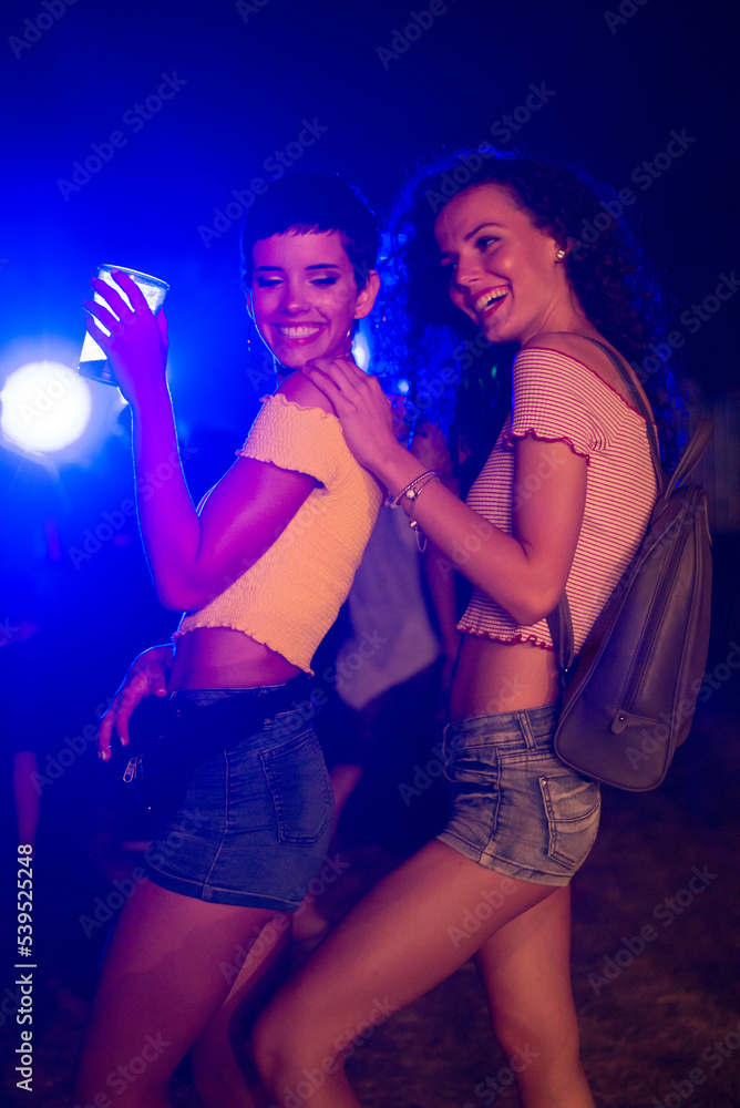 Two happy young girls dancing and drinking beer on the party concert in the night club Two happy young girls dancing and drinking beer on the party concert in the night club