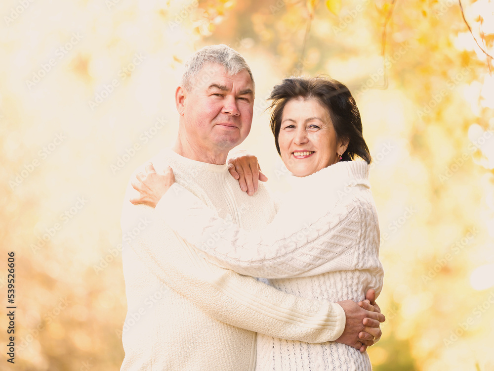 Beautiful happy pensioners are hugging in the autumn forest. Portrait