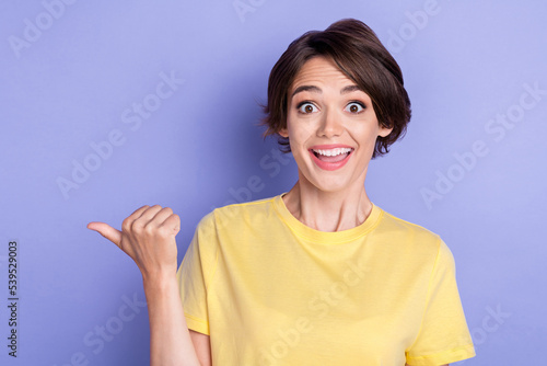 Portrait of astonished cheerful lady indicate thumb finger empty space offer isolated on purple color background