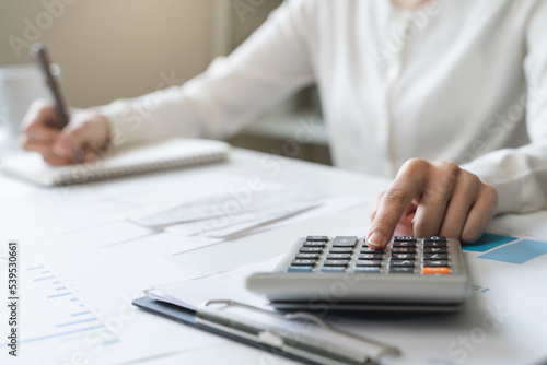 Women business people use calculators to calculate the company budget and income reports on the desk in the office.