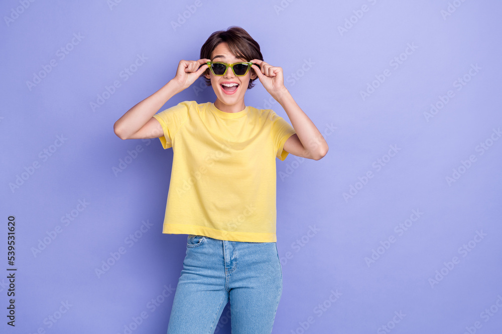Photo of young adorable gorgeous pretty woman wear yellow t-shirt denim hold new eyeglasses excited sun empty space ad isolated on violet color background