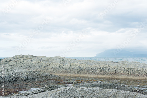 rocky seashore made of columnar basalt, hardened lava, resembling scales or cobblestone pavement, coast of Kunashir island