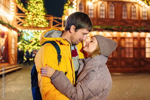 A young couple in love is enjoying the Christmas holidays on a city street. Holiday concept