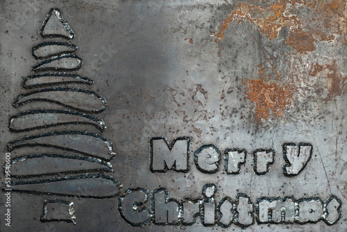 Hard phrase merry christmas made from steel letters welded to a steel sheet. Unusual Christmas card. Christmas card in heavy metal style. Copy space.