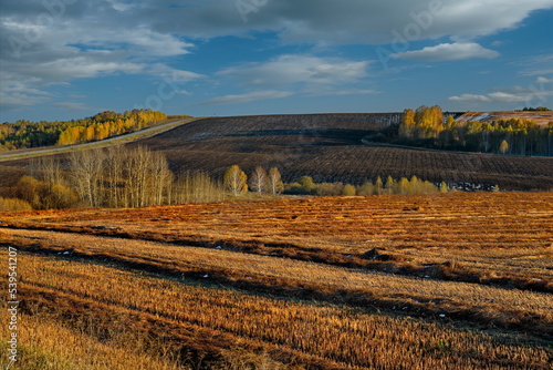 Russia. South of Western Siberia, Altai Krai. Autumn mown fields on the hilly border with Kuzbass, illuminated by the rays of the setting sun. photo