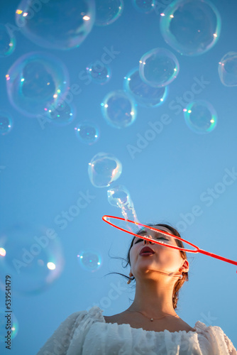 The girl blows soap bubbles against the blue sky.