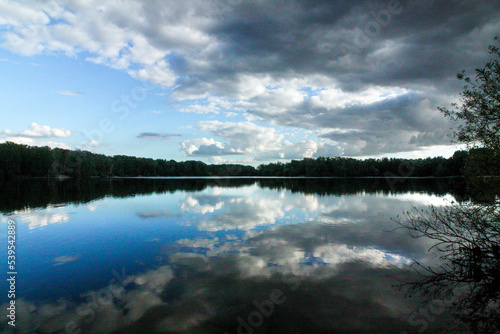 A walk on the lake with some clouds in the sky and a view across the water into the woods.