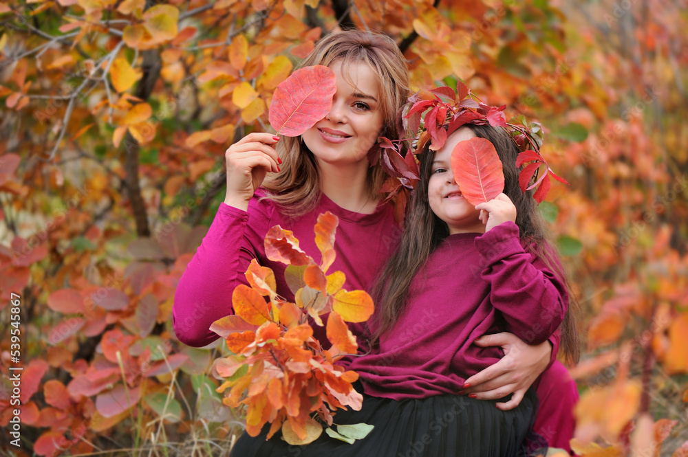 Mother and daughter holding autumn leafs against eyes Mother and daughter holding autumn leafs against eyes