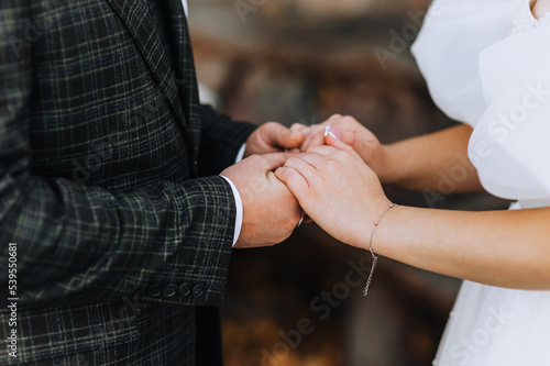 The bride and groom hold hands at the wedding ceremony close-up.