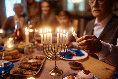 Fotografía Close up of senior man lighting menorah during family dinner on Hanukkah