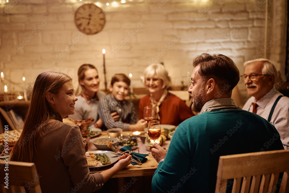 Happy father and daughter talking during family meal at dining table on Thanksgiving.