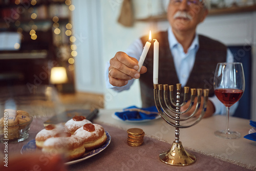 Close up of Jewish man lighting menorah during Hanukkah. photo