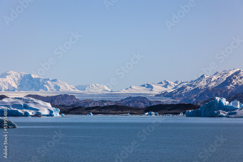 Paisaje apaisado glaciar entre montañas frente a lago photo