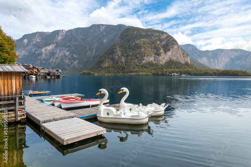 Fototapeta Naklejka Na Ścianę i Meble -  Two swan pedal boats wait for tourists at a small dock on the lake at Hallstatt, Austria.