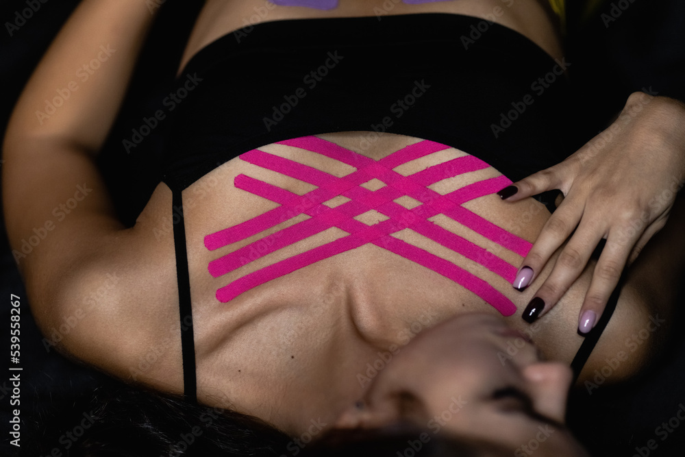 Obraz premium Cosmetology kinesio tapes on young woman breast. Body care modern treatment for tighten skin muscle tissue and improve blood circulation. Anti-cellulite. Sport. Beautiful body. Fit. Care.