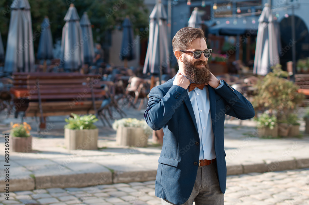 Stylish man with beard wearing a jacket, shirt adjusting his bow tie