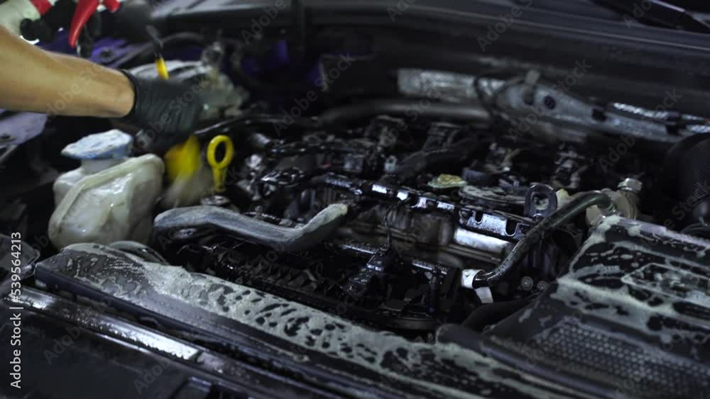 Washing car engine with brush and detergent in detailing auto service 4k video. Cleaning engine from dust and dirt. Washing car engine with brush and detergent in detailing auto service 4k video. Cleaning engine from dust and dirt.