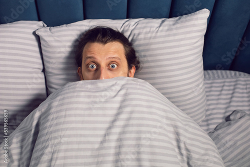 Εκτύπωση καμβά portrait of a man with a beard lying on the bed in the bedroom suffering from insomnia, lying with bulging eyes
