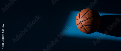 Brown new basketball ball with natural lighting on blue background. Sport team concept. Horizontal sport theme poster, greeting cards, headers, website and app © Augustas Cetkauskas
