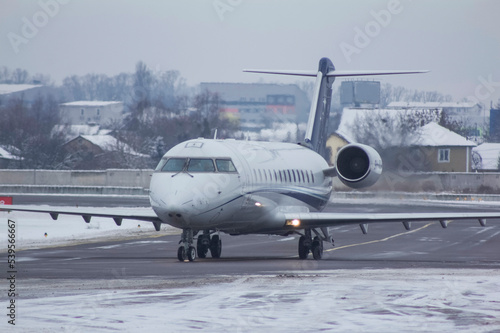 business jet plane is driving on the airport taxiway covered with snow in winter.