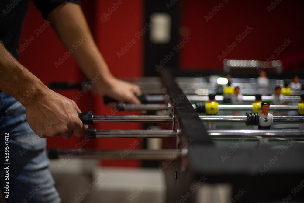 Freunde spielen zusammen Kicker am Kickertisch Freunde spielen zusammen Kicker am Kickertisch