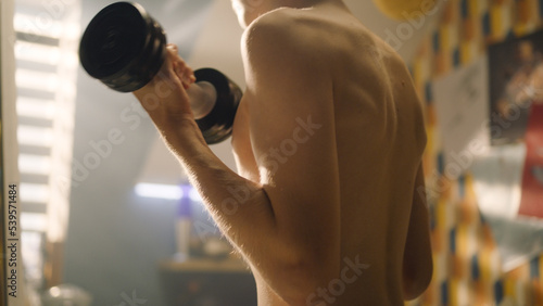 Fotografía Muscular schoolboy doing dumbbells curls in his room