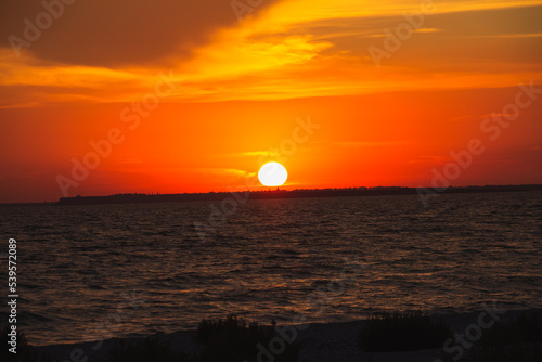 Fototapeta Naklejka Na Ścianę i Meble -  Amazing Black sea. Clouds and sand landscape background. Drama orange sky and red sun on horizon. Golden blue hour at the ocean romantic evening. Tropical island summer paradise. Wild rest in camp.
