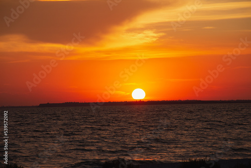 Fototapeta Naklejka Na Ścianę i Meble -  Amazing Black sea. Clouds and sand landscape background. Drama orange sky and red sun. Golden blue hour at the ocean romantic evening. Tropical island summer paradise. Wild rest in camp.