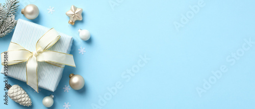 Christmas gift box with white ribbon bow, Christmas decorations, baubles, stars on pastel blue background. Christmas banner design, header template. Minimal style.