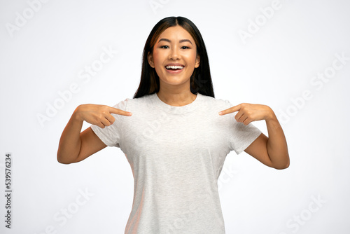 Photography Portrait of charming happy teenager girl in white T-shirt smiling and pointing a