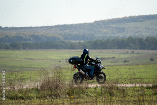 a motor cyclist  biker  riding their sports motorbike along a dusty summer stone track