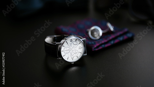 Business accessories. Mens watch and cufflinks isolated on black background.