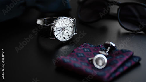 Business accessories. Mens watch and cufflinks isolated on black background.