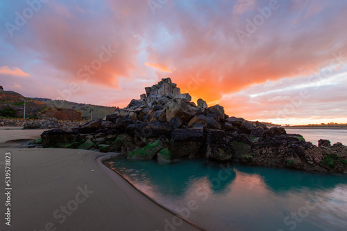 Colorful sunset clouds over Shag Rock, Christchurch, New Zealand.